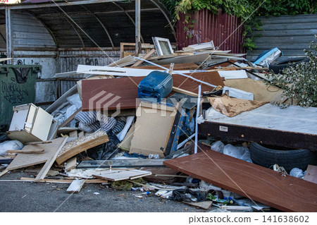 Mixed trash and debris on street - illegal waste disposal and environmental issue. Illegal dumping of household waste and furniture - urban pollution and environmental problem 141638602