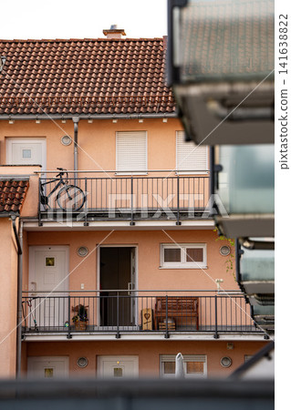 Bicycle Parked On Balcony Corridor: Residential Apartment Building With Orange Facade Exterior Bicycle Parked On Balcony Corridor: Residential Apartment Building With Orange Facade Exterior 141638822