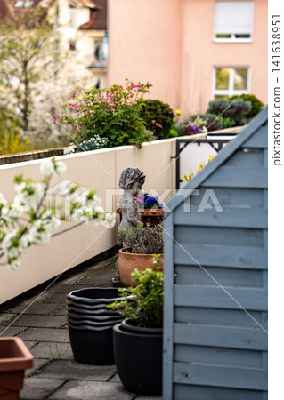 Stone Garden Statue Surrounded By Spring Flowers: Cozy Patio With Chrysanthemum And Geranium Plants Stone Garden Statue Surrounded By Spring Flowers: Cozy Patio With Chrysanthemum And Geranium Plants 141638951