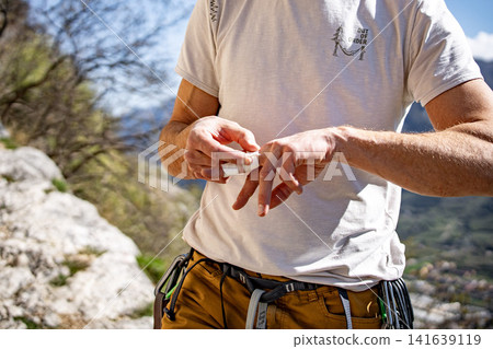 Male Climber Taping Fingers Before Route: Close Up Of Hands Preparing For Outdoor Rock Climbing Male Climber Taping Fingers Before Route: Close Up Of Hands Preparing For Outdoor Rock Climbing 141639119