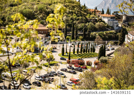 Elevated View Over Nago Town With Foreground Flowers: Scenic Hillside Landscape Near Lake Garda In Province Of Trento Italy Elevated View Over Nago Town With Foreground Flowers: Scenic Hillside Landscape Near Lake Garda In Province Of Trento Italy 141639131