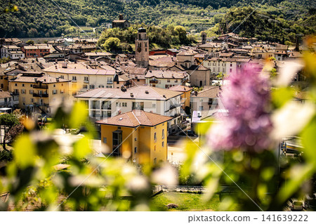 Elevated View Over Nago Town With Foreground Flowers: Scenic Hillside Landscape Near Lake Garda In Province Of Trento Italy Elevated View Over Nago Town With Foreground Flowers: Scenic Hillside Landscape Near Lake Garda In Province Of Trento Italy 141639222