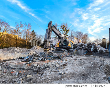 Excavator Demolishing Building Debris At Construction Site: Urban Development Scene In Munich Germany Excavator Demolishing Building Debris At Construction Site: Urban Development Scene In Munich Germany 141639240