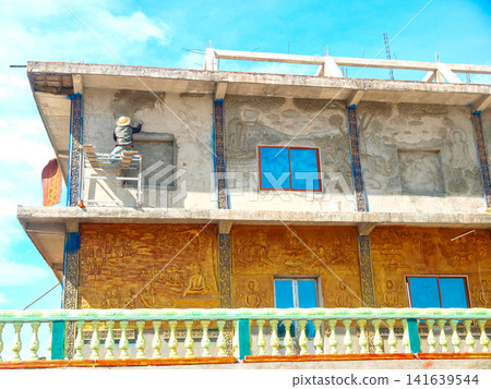 Ornate Residential Building Facade In Cambodia: Concrete Structure With Decorative Golden Panels And Blue Windows In Daylight Ornate Residential Building Facade In Cambodia: Concrete Structure With Decorative Golden Panels And Blue Windows In Daylight 141639544
