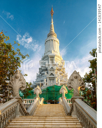 Ancient Stone Face Tower In Udong Cambodia: Historic Temple Monument Rising Above Lush Greenery At Golden Hour Ancient Stone Face Tower In Udong Cambodia: Historic Temple Monument Rising Above Lush Greenery At Golden Hour 141639547
