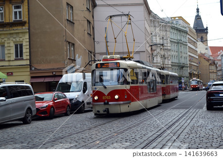 Front view of red Prague tram number six on a cobblestone road for urban transit banner and travel background 141639663