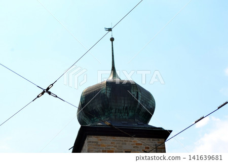 Copper onion dome tower with spire and overhead tram wires against clear sky for architectural detail background. Sitkov Water Tower in Prague 141639681