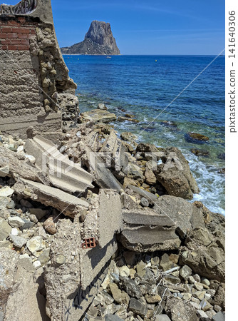 Scenic view of Penon de Ifach rock landmark by the sea and collapsed concrete ruins in Calpe, Spain Scenic view of Penon de Ifach rock landmark by the sea and collapsed concrete ruins in Calpe, Spain 141640306