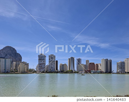 Calpe city skyline reflects in salt lake waters under a bright summer sky Calpe city skyline reflects in salt lake waters under a bright summer sky 141640483