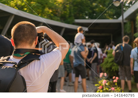 Photographer Covers an Outdoor Public Event . Photographer uses digital camera to document people attending an outdoor public event in garden venue Photographer Covers an Outdoor Public Event . Photographer uses digital camera to document people attending an outdoor public event in garden venue 141640795