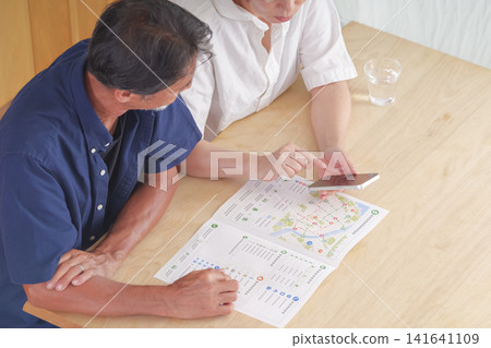 A couple discusses disaster preparedness using a disaster prevention map. 141641109
