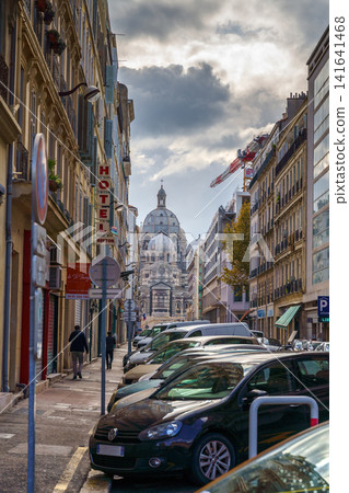 Marseille, France - Nov 3 2018, vertical view of a narrow street filled with parked cars, in the background Cathedrale Sainte Marie Majeure de Marseille, at daytime with cloudy sky, Marseille, France Marseille, France - Nov 3 2018, vertical view of a narrow street filled with parked cars, in the background Cathedrale Sainte Marie Majeure de Marseille, at daytime with cloudy sky, Marseille, France 141641468