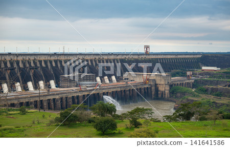 The power generation facilities and dam structure of the Itaipu hydroelectric power plant spread out beneath the thick clouds. The power generation facilities and dam structure of the Itaipu hydroelectric power plant spread out beneath the thick clouds. 141641586