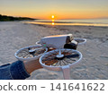 Hand Holding Camera Drone on Beach at Sunset 141641622