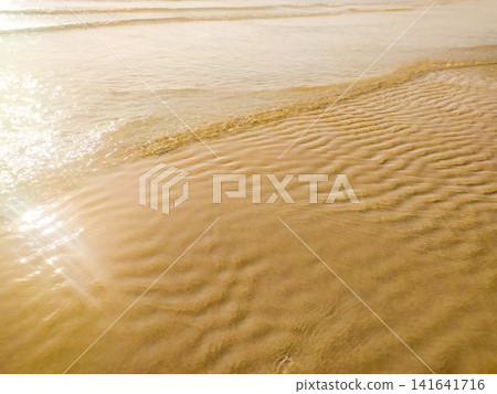 Gentle waves wash over golden sand at sunset, creating a serene, meditative atmosphere. This tranquil coastal scene with no people captures nature's calm beauty, perfect for relaxing projects. Gentle waves wash over golden sand at sunset, creating a serene, meditative atmosphere. This tranquil coastal scene with no people captures nature's calm beauty, perfect for relaxing projects. 141641716