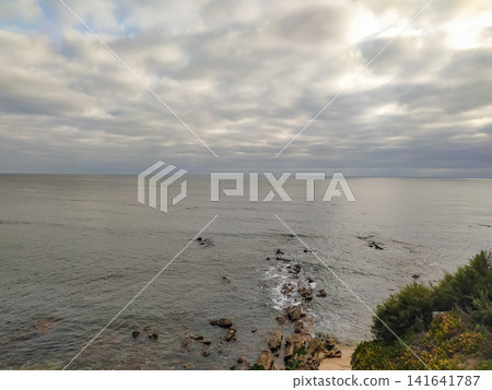 A serene, vast seascape at dusk, featuring calm waters, jagged rocks, and a cloudy sky. Nobody present in this peaceful coastal scene, evoking tranquility and natures timeless beauty, ideal. A serene, vast seascape at dusk, featuring calm waters, jagged rocks, and a cloudy sky. Nobody present in this peaceful coastal scene, evoking tranquility and natures timeless beauty, ideal. 141641787