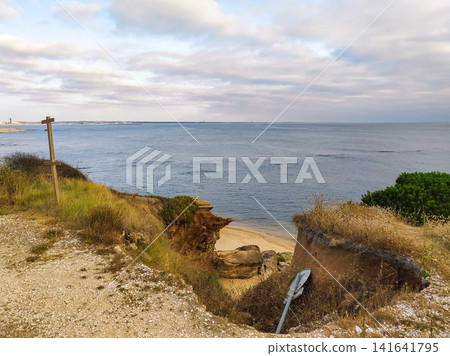 A coastal view from a cliff edge overlooking the ocean with nobody in sight. The rugged landscape and signpost evoke a sense of peaceful solitude, perfect for themes of travel, nature, and escape. A coastal view from a cliff edge overlooking the ocean with nobody in sight. The rugged landscape and signpost evoke a sense of peaceful solitude, perfect for themes of travel, nature, and escape. 141641795