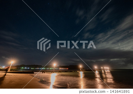 Night view of a pier lined with streetlights and a starry sky (long exposure at the beach) Night view of a pier lined with streetlights and a starry sky (long exposure at the beach) 141641891