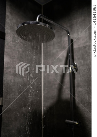 Overhead shower. Water falling from the bathroom rain shower. Black tiled wall. Overhead shower. Water falling from the bathroom rain shower. Black tiled wall. 141641963