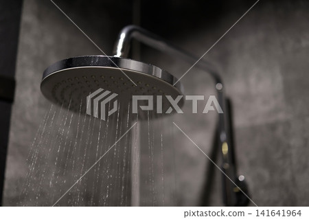 Overhead shower. Water falling from the bathroom rain shower. Black tiled wall. 141641964