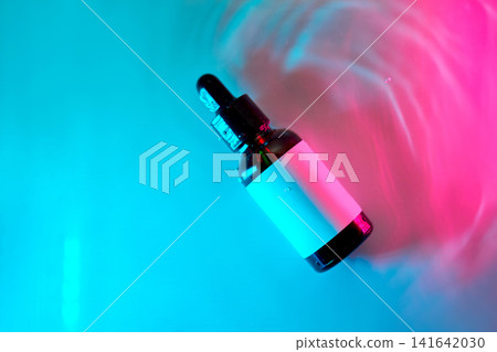 Cosmetics serum dropper bottle floating in neon water Cosmetics serum dropper bottle floating in neon water 141642030