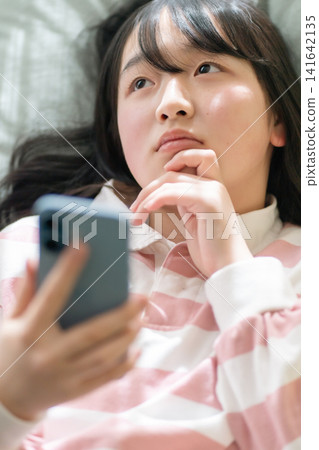 High school students relaxing in their rooms with their smartphones (Gen Z, lifestyle, apps, advertising material) 141642135