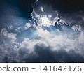 A dramatic sky with sunlight shining through the clouds and dark rain clouds. 141642176