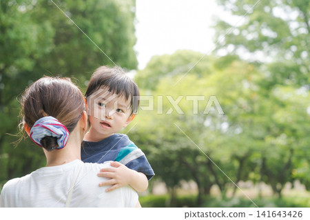 公園裡,媽媽抱著一個小男孩。 公園裡,媽媽抱著一個小男孩。 141643426