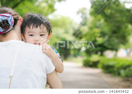 公園裡,媽媽抱著一個小男孩。 公園裡,媽媽抱著一個小男孩。 141643432