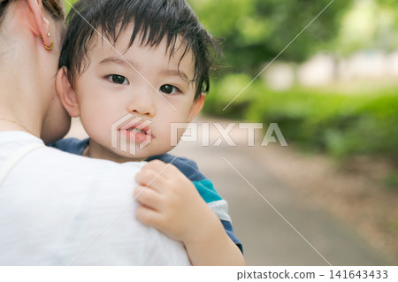 公園裡,媽媽抱著一個小男孩。 公園裡,媽媽抱著一個小男孩。 141643433