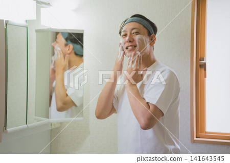 一位四十多歲的男子在浴室裡用泡沫洗臉時面帶微笑。 一位四十多歲的男子在浴室裡用泡沫洗臉時面帶微笑。 141643545