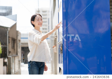 A woman buying a drink from a vending machine. A woman buying a drink from a vending machine. 141643636