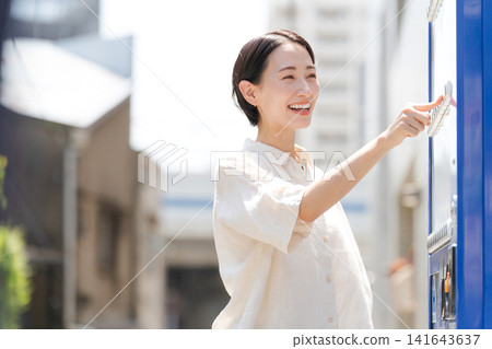 A woman buying a drink from a vending machine. A woman buying a drink from a vending machine. 141643637