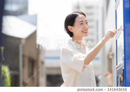 一位女士正在自動販賣機購買飲料。 一位女士正在自動販賣機購買飲料。 141643638