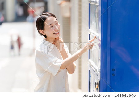 A woman buying a drink from a vending machine. A woman buying a drink from a vending machine. 141643640