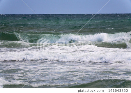 Waves crashing against the shore, sending up white spray. Waves crashing against the shore, sending up white spray. 141643860