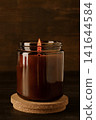 Candle in glass jar on wooden background, space for text 141644584