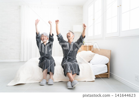 Senior couple sitting on the bed in a gown coat Lifestyle image Senior couple sitting on the bed in a gown coat Lifestyle image 141644623