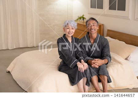 一對老年夫婦穿著長袍坐在床上,生活方式圖片 一對老年夫婦穿著長袍坐在床上,生活方式圖片 141644657