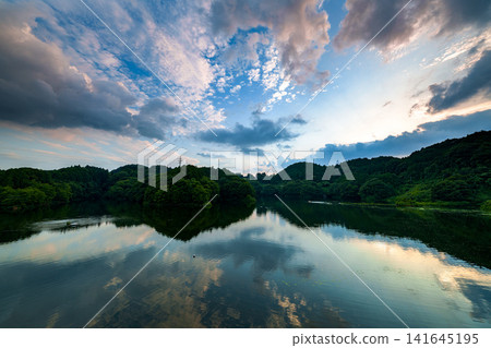 Sunset view of Lake Nunome to the south from the Nunome Dam embankment in Nara City, Nara Prefecture. Ultra-wide-angle zoom lens. The changing sunset sky ⑤ Sunset view of Lake Nunome to the south from the Nunome Dam embankment in Nara City, Nara Prefecture. Ultra-wide-angle zoom lens. The changing sunset sky ⑤ 141645195