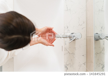 Woman washing her hands in the bathroom Lifestyle image Woman washing her hands in the bathroom Lifestyle image 141645291