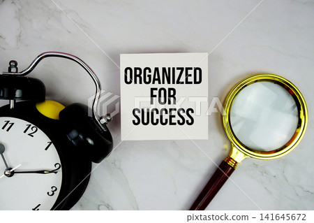 Organized For Success text with sticky note and alarm clock flat lay on marble background Organized For Success text with sticky note and alarm clock flat lay on marble background 141645672
