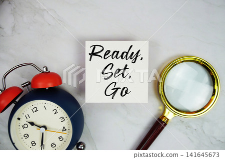 Ready, Set, Go text with sticky note and alarm clock flat lay on marble background Ready, Set, Go text with sticky note and alarm clock flat lay on marble background 141645673