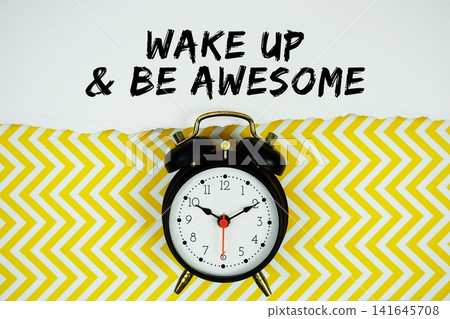 Wake Up and Be Awesome text written on paper with alarm clock on yellow chevron background Wake Up and Be Awesome text written on paper with alarm clock on yellow chevron background 141645708