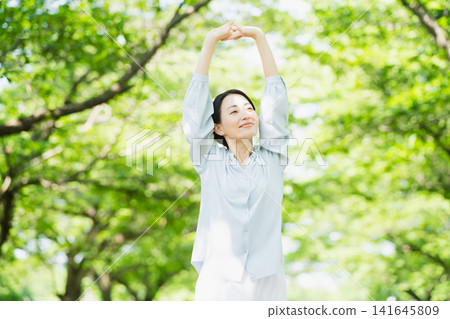 Young woman stretching under a tree Lifestyle image Young woman stretching under a tree Lifestyle image 141645809