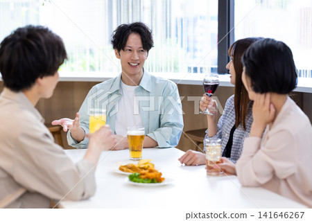 飲酒聚會:男男女女一邊聊天一邊喝酒。 飲酒聚會:男男女女一邊聊天一邊喝酒。 141646267