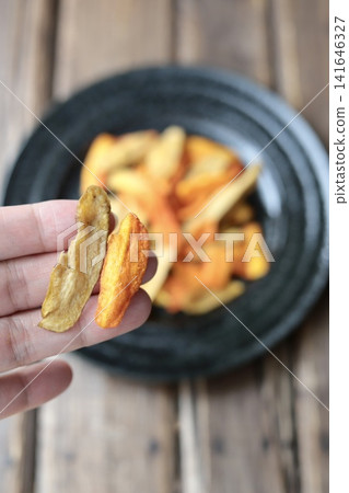 醬油口味炸牛蒡胡蘿蔔片;手指沾著蔬菜片 醬油口味炸牛蒡胡蘿蔔片;手指沾著蔬菜片 141646327