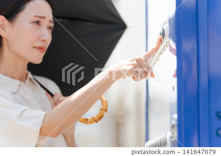A woman buying a drink from a vending machine on a hot day. A woman buying a drink from a vending machine on a hot day. 141647079