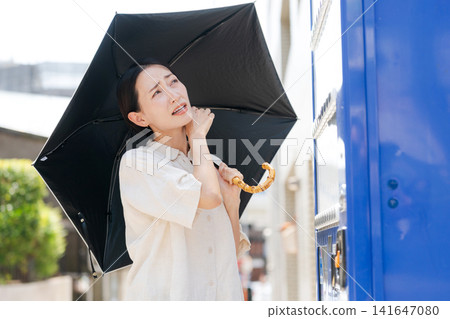 A woman buying a drink from a vending machine on a hot day. A woman buying a drink from a vending machine on a hot day. 141647080