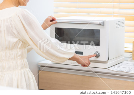 Meals: Senior women warming up their packed lunches at home. Meals: Senior women warming up their packed lunches at home. 141647300